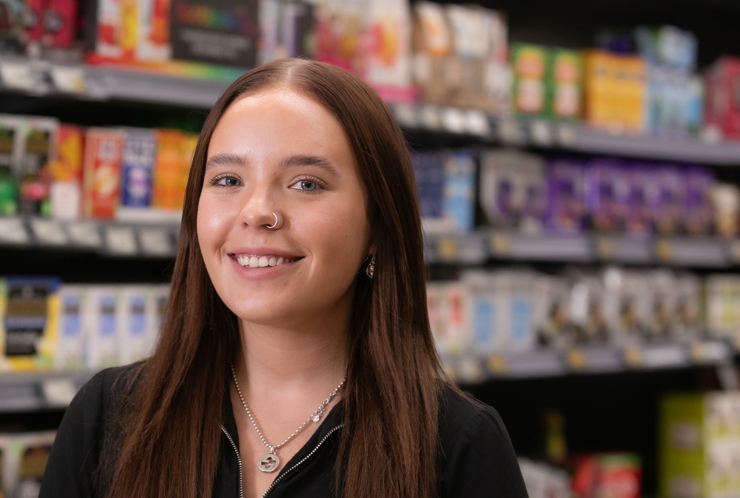 Store colleague smiling in front of shelves