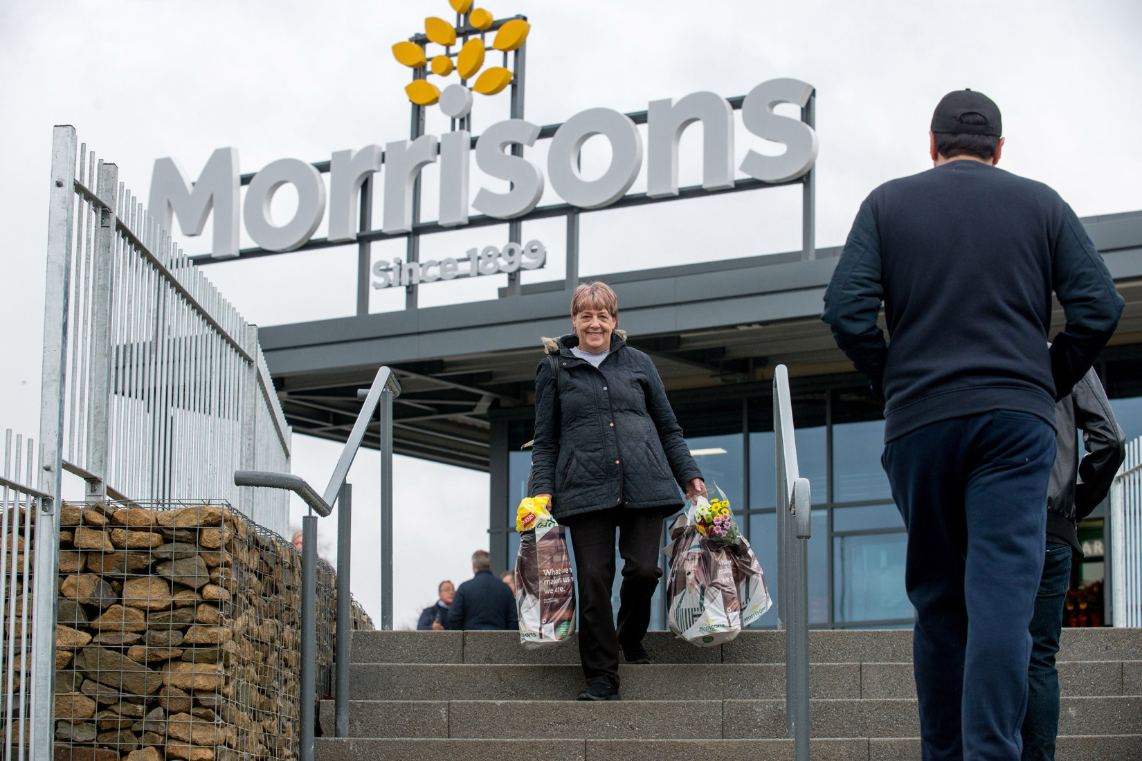 Customer carrying bags of shopping out of a Morrisons store