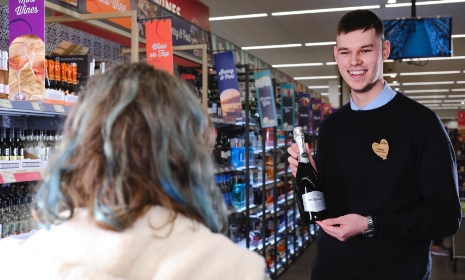 Colleague holding prosecco talking to customer